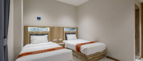 A hotel room with two beds, wooden headboards, white bedding, and a small bedside table.