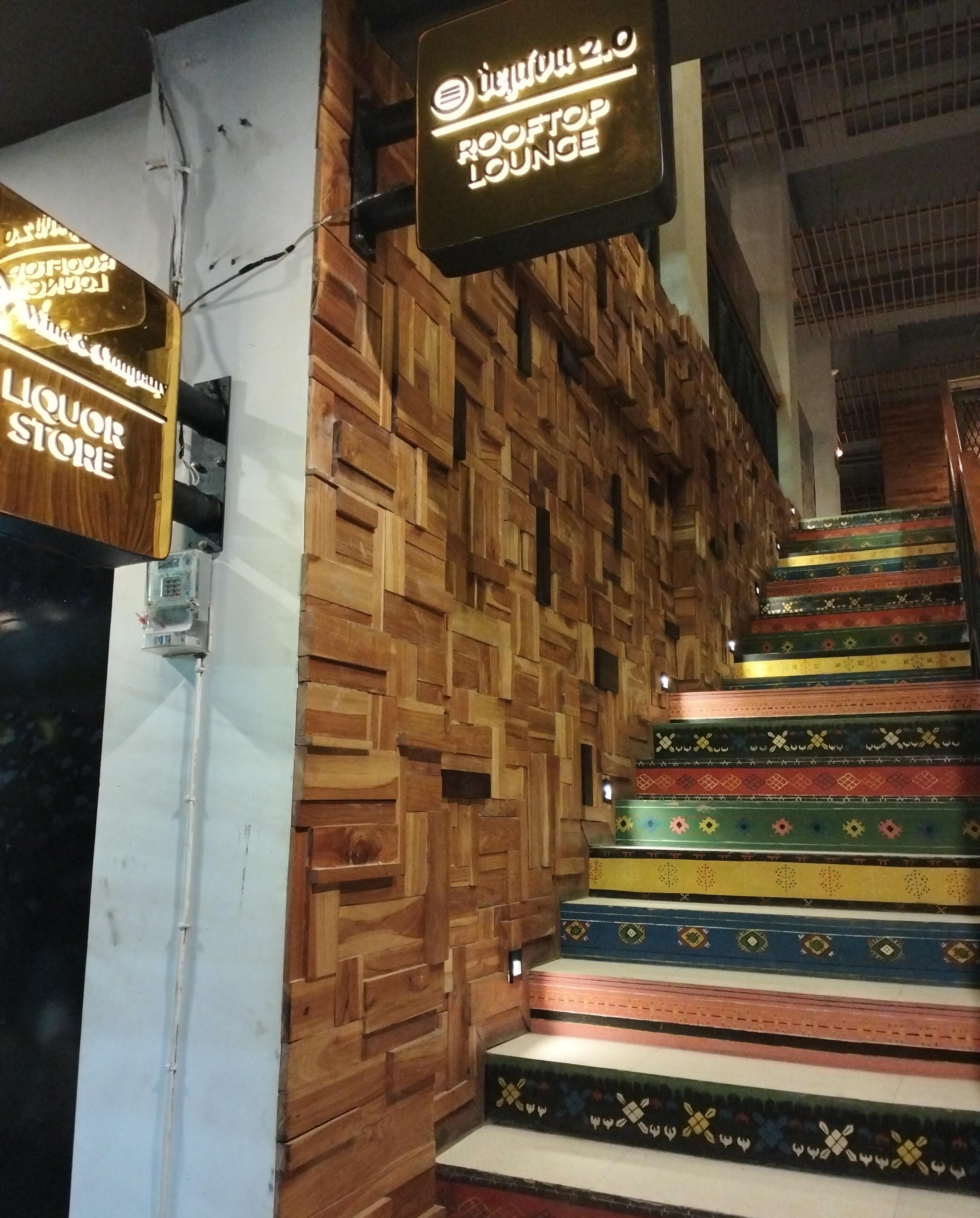 A staircase with a wooden wall and a sign for the Rooftop Lounge.