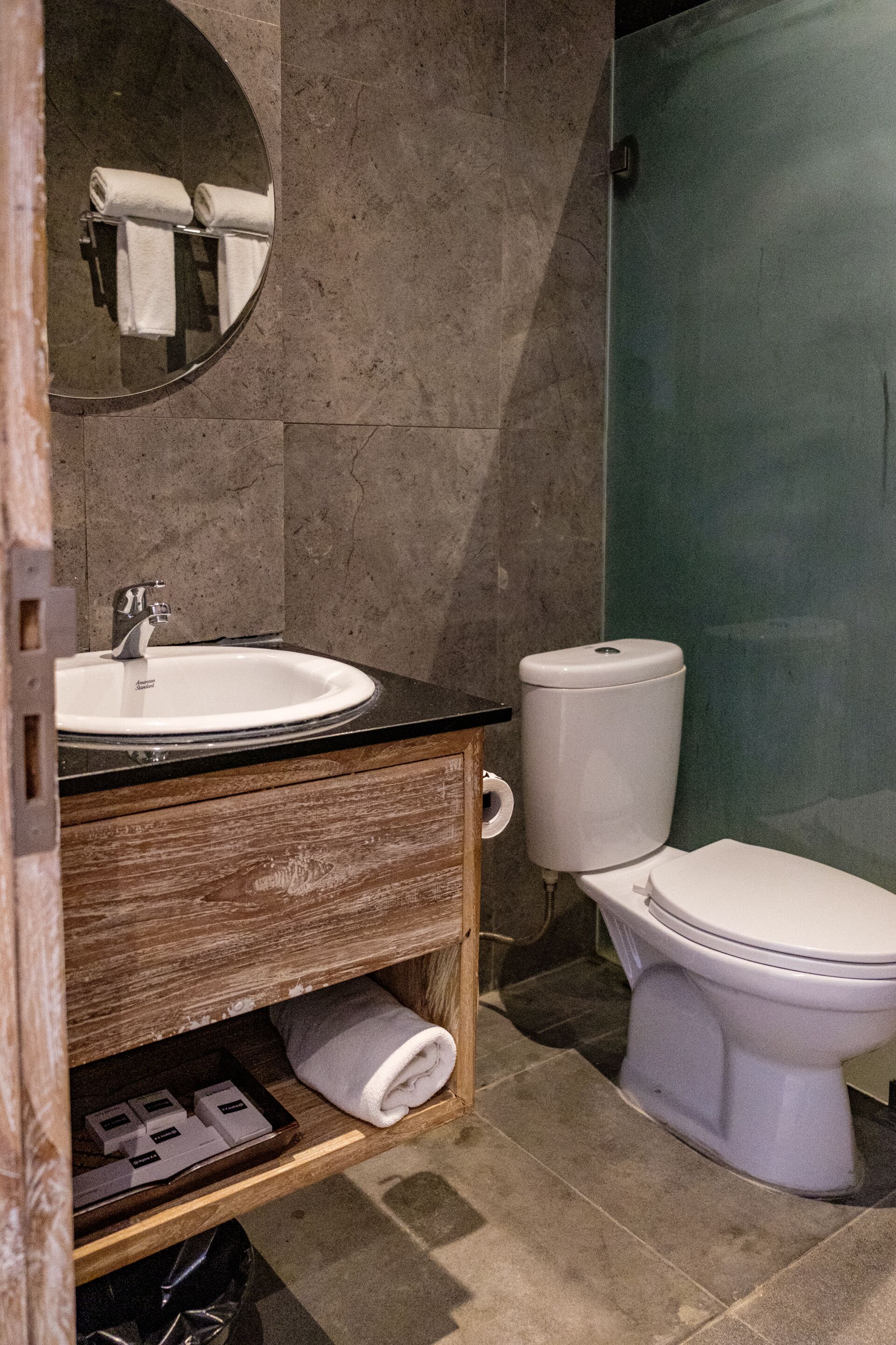A bathroom with a white sink, wooden vanity, a toilet, and a mirror.