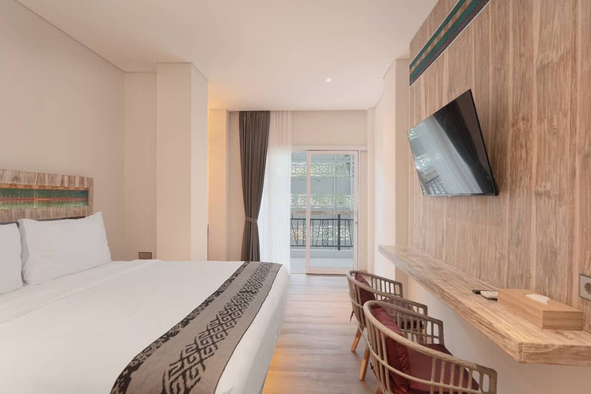 Ein Hotelzimmer mit einem großen Bett, einem an der Wand montierten Fernseher, einem Balkon mit Blick und einer Wand mit Holzverkleidung.