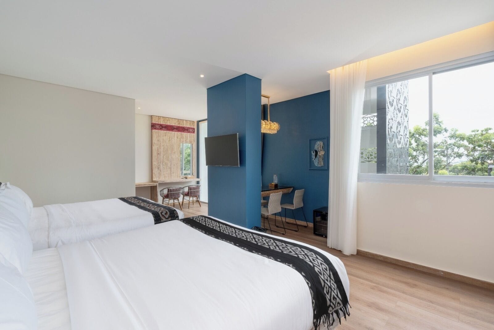 A hotel room with a large bed, a desk with a chair, a TV, and a window with a view.