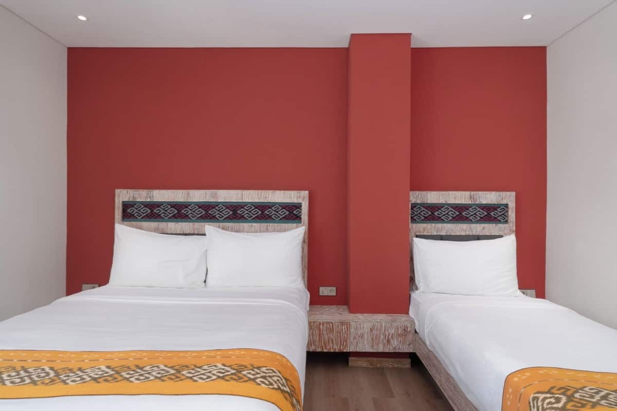 Ein Hotelzimmer mit zwei Betten, roten Wänden und einem hölzernen Kopfstück.