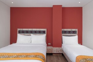 Habitación de hotel con dos camas, paredes rojas y cabecero de madera.