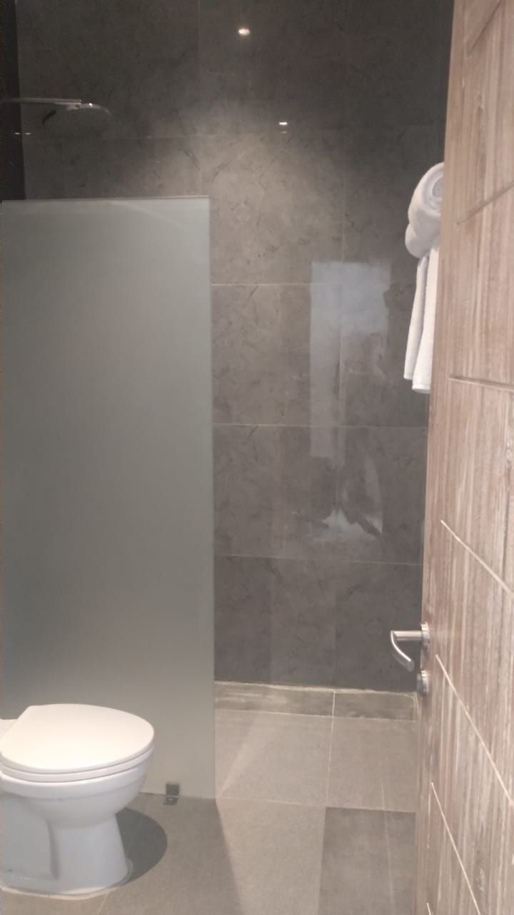 Une salle de bain avec des toilettes, un espace douche et un mur en bois.