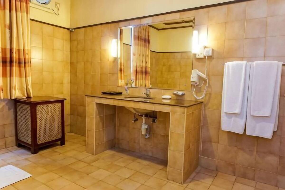 A bathroom with a sink, mirror, towel rack, and a small cabinet.