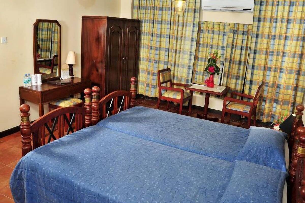 A bedroom with a bed, a desk, a chair, a wardrobe, and a mirror.