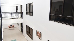 Un interior de varios niveles con un espacio central abierto, un banco, una planta en maceta y un cuadro en la pared.