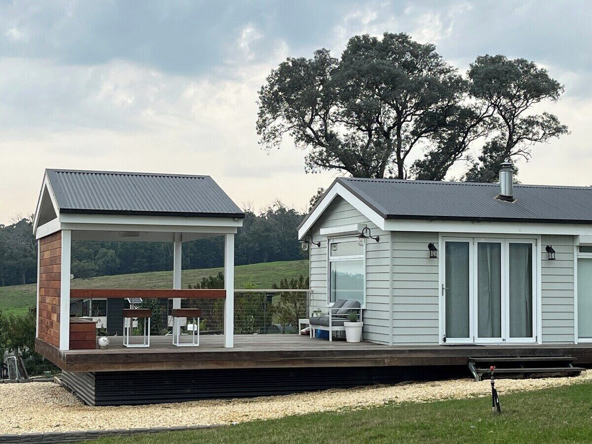 A modern house with a covered outdoor area, a deck, and a large window.
