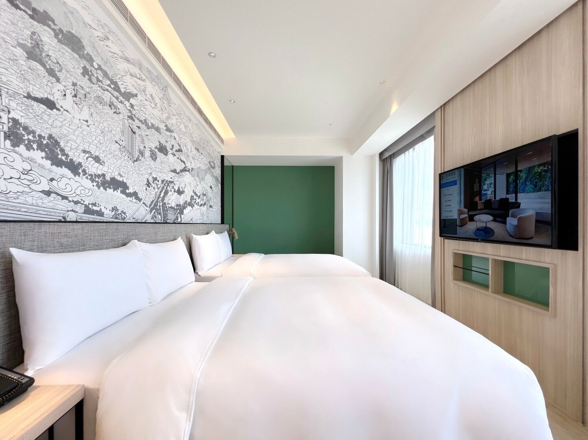Una habitación de hotel moderna con una cama grande, un televisor de pantalla plana y una pared de acento verde.