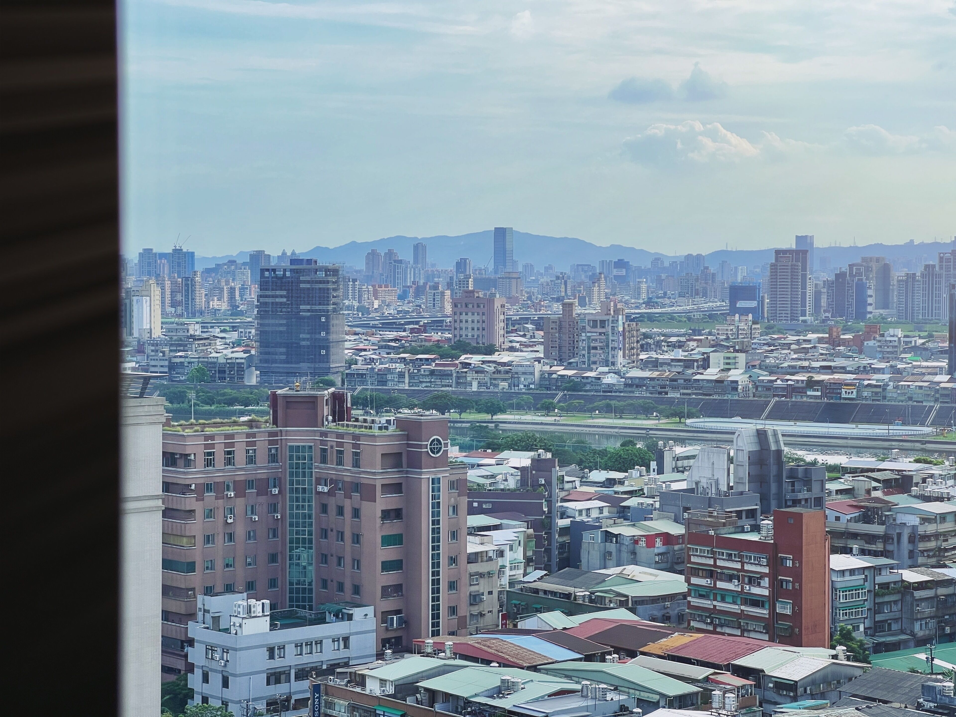 A cityscape with high-rise buildings, a river, and distant mountains.