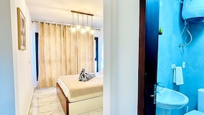 A modern bedroom with a bed, a chandelier, and a bathroom with a toilet and sink. - Beachfront Chalet in Porto Said With Pool & Gar (Al-Manasrah)