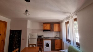 A compact kitchen with wooden cabinets, a washing machine, a microwave, and a sink. - Casa Luisa With Pool (Alghero)