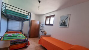 A dormitory room with bunk beds, a wardrobe, a desk, a chair, a fan, a window, and a picture on the wall. - Casa Luisa With Pool (Alghero)