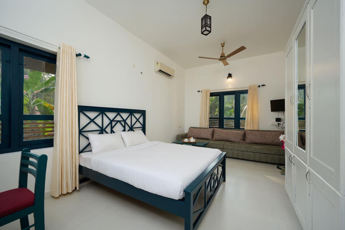 A bedroom with a bed, a sofa, a chair, and a wardrobe.