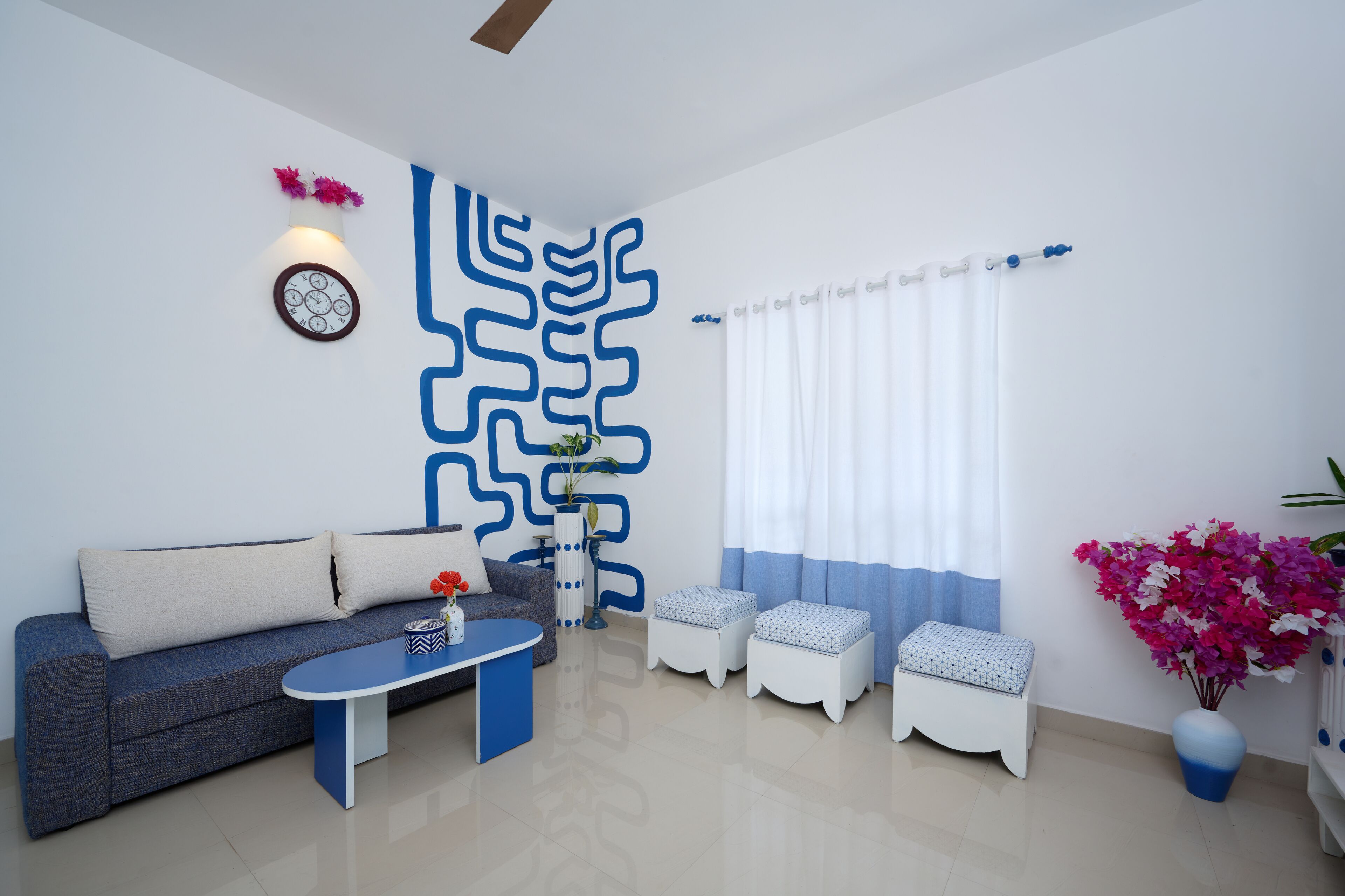 A modern living room with a sofa, coffee table, and two white ottomans.