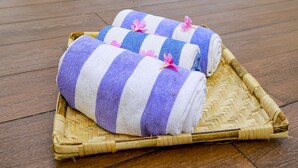 Una terraza de madera con piscina, una silla de descanso y una cesta de mimbre con toallas.