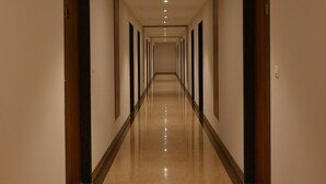 A long, narrow hotel corridor with doors on both sides and a shiny floor. - M D Farms & Resorts (Mathura)