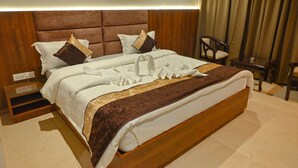 A neatly made bed with a brown headboard, white linens, and decorative pillows. - M D Farms & Resorts (Mathura)