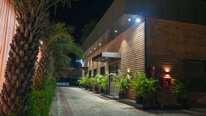 A modern building with a brick facade and a paved walkway lined with potted plants. - M D Farms & Resorts (Mathura)