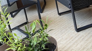 A corner of a room with two wicker chairs, a potted plant, and a brick wall. - House Valentina (Perugia)