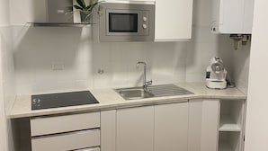 A modern kitchen with white cabinets, a built-in microwave, a sink, and a coffee machine. - House Valentina (Perugia)