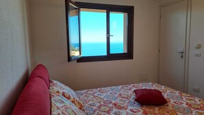 Un dormitorio con cama, ventana con vista al mar y una puerta.