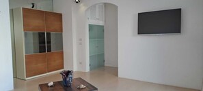 Ein Zimmer mit Kleiderschrank, Flachbildfernseher und einem kleinen Tisch mit Dekoration.