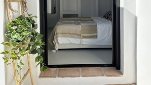 Un dormitorio con una cama, una planta colgante y una escalera de madera.