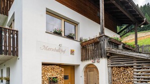 Un bâtiment sur lequel on peut lire l’inscription « Marshalkhof », doté de balcons en bois et où l’on aperçoit une pile de bois de chauffage.
