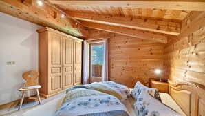 Une chambre dans une cabane en bois, avec deux lits, une armoire, une chaise et une fenêtre.