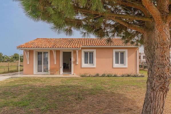 Un bâtiment d’un seul étage, doté d’un toit en tuiles, d’une porte d’entrée et d’un petit porche avec des chaises.