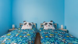 Una habitación con dos camas, cada una con un cojín con estampado de panda, frente a una pared azul.
