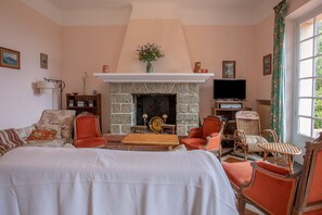 A living room with a fireplace, a television, and a large window.