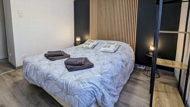 Ein modernes Schlafzimmer mit einem Bett, zwei Nachttischlampen und einer Wand aus Holzlatten.