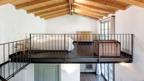 Un dormitorio tipo loft con techo de madera, una cama, un aparador y una maleta.