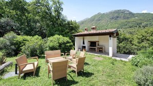 Un patio con mobiliario de mimbre, una chimenea y vistas a un paisaje montañoso.