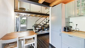 Una cocina moderna con armarios blancos, una mesa de comedor de madera y una escalera que sube a un nivel superior.