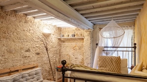 A rustic room with a bed, a shelf with kitchenware, a hanging light fixture, and a window with a white curtain. - Holiday Home 'Il Pescino' with Private Terrace and Wi-Fi (Pietrasanta)