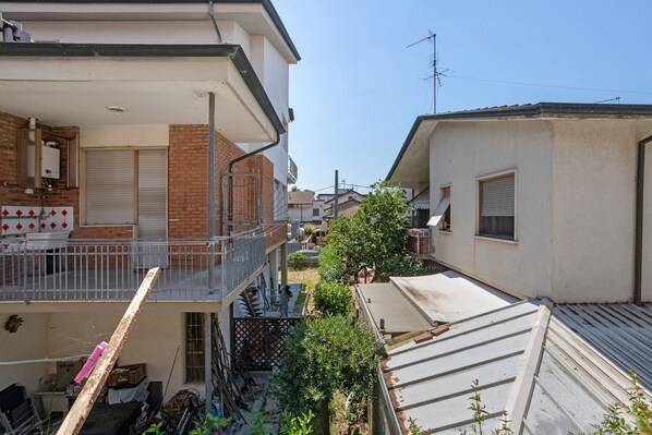 Zona residencial con balcón, garaje y un pequeño jardín.