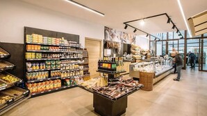 En mataffärs interiör med hyllor fyllda med olika produkter, ett centralt placerat skyltfönster och en väl synlig entré.