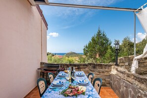 Une table dressée pour le dîner, avec vue sur la mer et les collines.