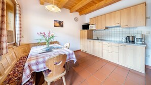 Un interno in legno con un tavolo da pranzo, sedie, un orologio e un angolo cottura dotato di mobili ed elettrodomestici.