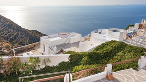 Un edificio blanco con terraza vista al mar, una hamaca y mobiliario exterior.