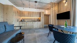 Eine moderne Küche mit Holzschränken, einem Einbauherd und einem flachbildfernseher an der Wand.
