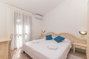 Una habitación de hotel con una cama, una silla, un escritorio y una ventana con cortinas.