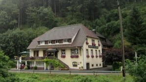 Um edifício de dois andares com telhado inclinado, varanda e uma placa indicando que é um restaurante.