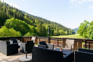An outdoor patio with wicker furniture and a view of a forested valley. - BLACK FOREST FAMILY APARTMENT (Bad Rippoldsau-Schapbach)