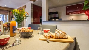 A dining area with a table set for breakfast, including croissants, a bottle of orange juice, and a vase with flowers. - Cozy apartment for 6 with parking in Grand-Bornand (Le Grand-Bornand)