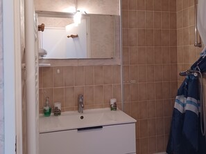 A bathroom with a white sink, two faucets, a mirror, and a shower curtain. - 2-room apartment with balcony, near beach and parking (Villers-sur-Mer)