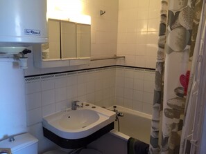 Une salle de bain avec un lavabo blanc, un miroir et une baignoire.